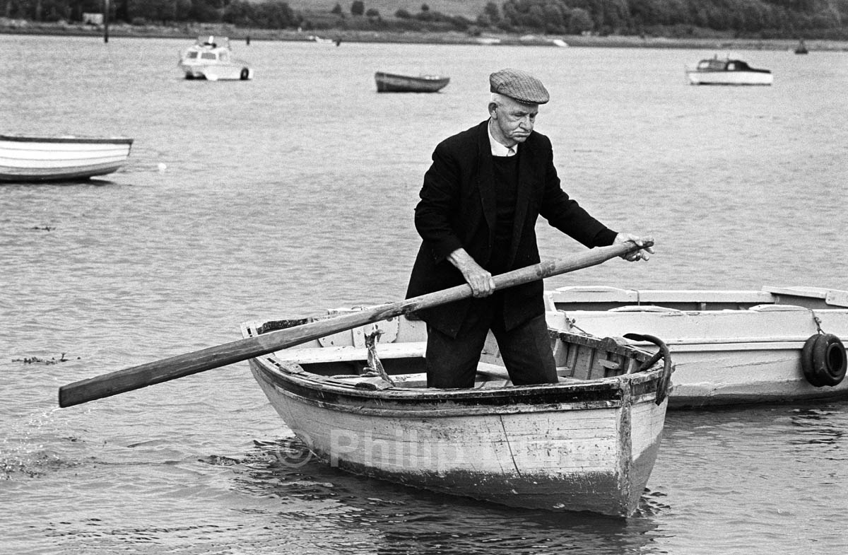 Old Irish man with one oar in a small boat