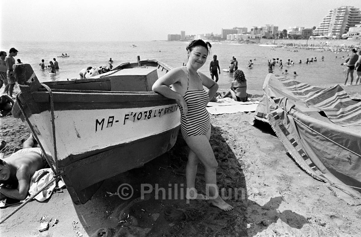 A young lady in striped swimming costume poses for photograph on Spanish beach