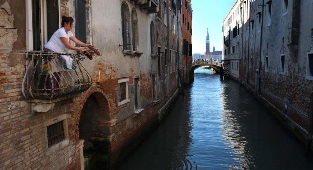 street photography Venice Rio della Pietra. Woman on balcony above canal