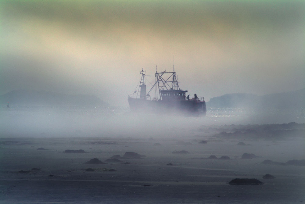 Scallop trawler heads home through fog on the River Dee, Kirkcudbright, Galloway