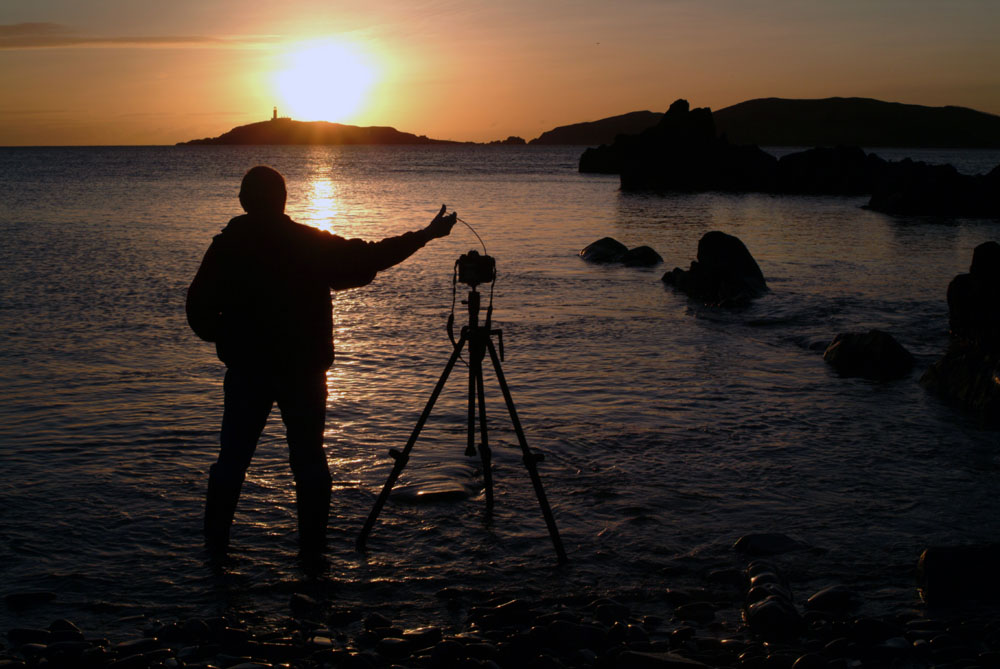 photographer takes pictues of a sunset on the coast